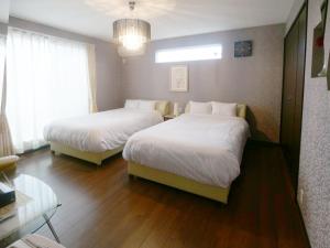 ein Zimmer mit zwei Betten und einem Tisch und ein Zimmer mit in der Unterkunft Masuyama in Gotemba