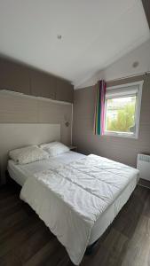 una camera da letto con un grande letto bianco con una finestra di Mobil Home 220 aménagé 2 chambres la teste camping 4 etoiles a La Teste-de-Buch