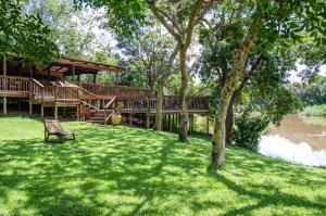 a house with a deck and a bench in the grass at Hippo Waterfront Lodge in Nelspruit