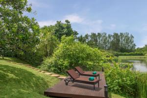 a bench sitting in the grass next to a pond at Banyan Tree Phuket in Bang Tao Beach