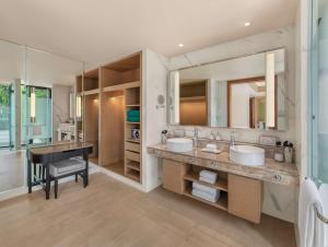 a bathroom with two sinks and a desk and a mirror at Banyan Tree Phuket in Bang Tao Beach