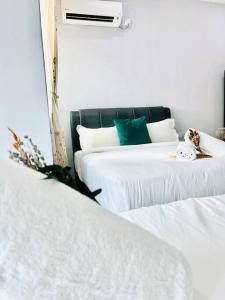 a bedroom with two beds with white sheets and green pillows at Kuantan Setali ROOMSTAY by Iconique in Kuantan