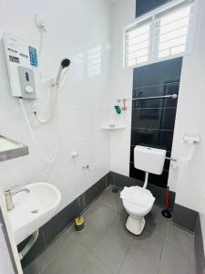 a white bathroom with a toilet and a sink at Kuantan Setali ROOMSTAY by Iconique in Kuantan