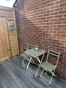 a table and two chairs next to a brick wall at Hot tub hideaway in Manchester