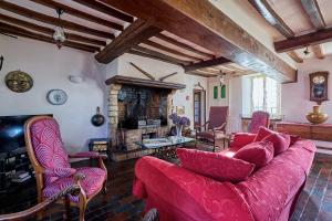 un soggiorno con un divano rosso e un camino di La Ferme de la Chapelle Saint-Roch - Maison de 190 m2 a Isigny-sur-Mer