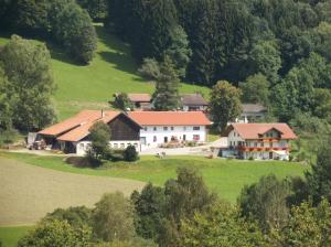 une grande maison blanche sur une colline verdoyante plantée d'arbres dans l'établissement Ferienwohnung Lindenhof, à Sankt Englmar