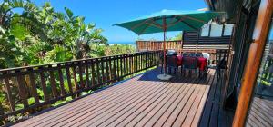 una terrazza con due sedie e un ombrellone di Milkwood Lodge 2 - Sleeps 8 a Port Edward