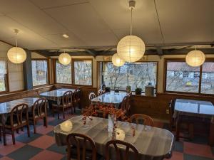a dining room with tables and chairs and lights at Guest house Maroudo in Iiyama