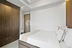 a bedroom with a white bed and a wooden wall at Bosco by Kozystay - Fatmawati in Jakarta +31 photos