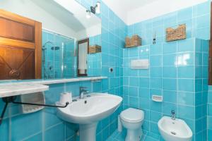 a blue tiled bathroom with a sink and a toilet at Le Giare 2 in La Maddalena +17 photos