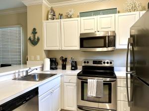 una cucina con armadietti bianchi, piano cottura e forno a microonde di Seas the Keys Getaway a Duck Key
