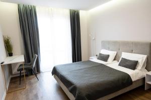 a bedroom with a bed and a desk and a window at Luxury Apartments “Bozdosh” in Uzhhorod