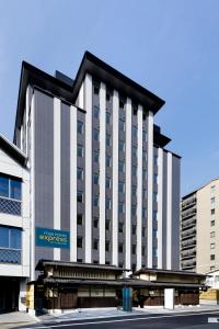 a large white building with a blue sign on it at Four Points Flex by Sheraton Kyoto Oike in Kyoto