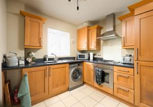 a kitchen with wooden cabinets and a washer and dryer at Stylish Flat With Sofa Bed in Malmesbury! in Malmesbury