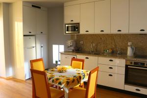 a kitchen with a table with yellow chairs and white cabinets at Casa Tia Etelvina in Castro Daire