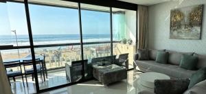 een woonkamer met een bank en uitzicht op de oceaan bij Appartement La perle de Mehdia, sea view in Kenitra