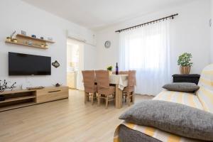 ein Wohnzimmer mit einem TV und einem Esstisch in der Unterkunft Apartment Andjelko G in Šilo
