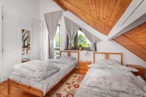 two beds in a bedroom with wooden ceilings and windows at Domek letniskowy Patricia in Sulęczyno