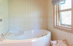 a white bath tub in a bathroom with a window at Nice Home In Lindesnes With Sauna in Svenevik +29 photos