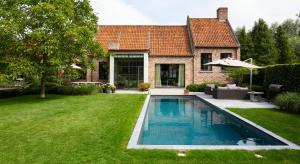 a swimming pool in the yard of a house at B&B Het Soetewater in Beernem