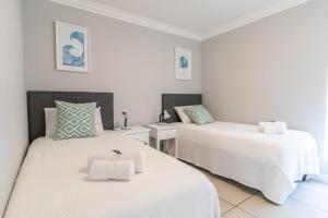 two beds in a room with white walls at NeverEndingStory in Yzerfontein