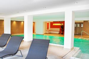 una piscina en un hotel con sillas azules en Gartenhotel Feldeck en Lauchringen