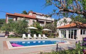 a house with a swimming pool in front of a house at Apartments Zeljka B in Mundanije