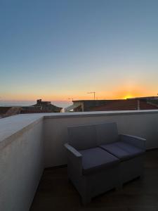 a bench on a balcony with the sunset in the background at B&B Casa CamiLory in San Lucido