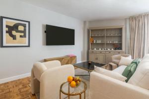 un soggiorno con mobili bianchi e TV a schermo piatto di Cervantes Luxury Apartment a Málaga