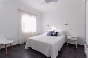 a white bedroom with a bed and a window at Apartamentos Gama in Cala Galdana