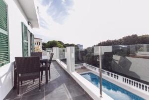 a balcony with a table and chairs and a swimming pool at Apartamentos Gama in Cala Galdana