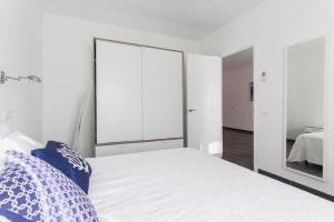 a bedroom with a white bed and a mirror at Apartamentos Gama in Cala Galdana