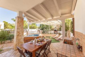 an outdoor patio with a wooden table and chairs at Villetta Camelia in Marina di Mancaversa