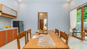 a dining room with a wooden table and chairs at Suweca House in Ubud
