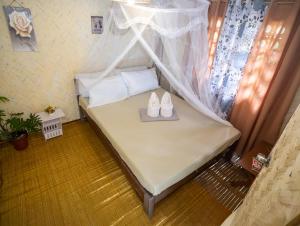 a small bed with two pairs of shoes on it at Femya Homestay in El Nido