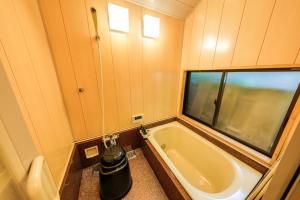 a small bathroom with a tub and a window at Tsukihitei in Nara