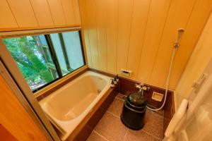 a bath tub in a small bathroom with a window at Tsukihitei in Nara