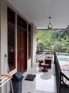 a balcony of a house with a table and benches at Jungle and River View in Bukit Lawang