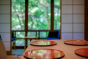 three red plates sitting on a table with a window at Tsukihitei in Nara