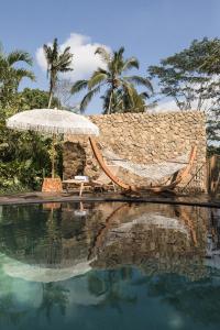 ウブドにあるBELALU Bali Boutique & SPA experienceのスイミングプール(ハンモック、パラソル付)