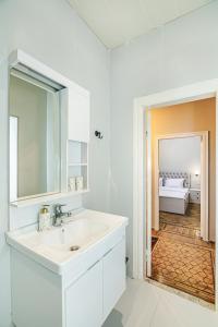 a white bathroom with a sink and a mirror at White Lilies Spacious 2-Bedroom Sea View in Baku