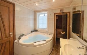 a large white tub in a bathroom with a sink at Beautiful Home In Sjusjøen With Sauna in Sjusjøen