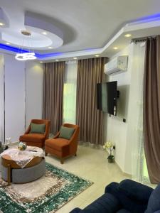 a living room with two chairs and a tv at Pyramid Heights Apartments in Cairo