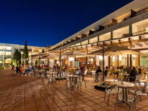 a group of tables and chairs in front of a building at Hotel Fuerte Conil-Resort in Conil de la Frontera