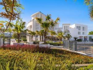 a large white building with palm trees and flowers at Hotel Fuerte Conil-Resort in Conil de la Frontera