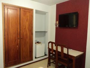 Habitación con mesa y TV en una pared roja. en MAGA PLAZA HOTEL, en São José do Rio Pardo