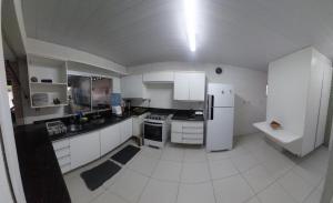 a kitchen with white cabinets and a white refrigerator at Quarto em Guarapari 5 min da praia in Guarapari
