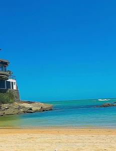 a beach with a house and the ocean at Quarto em Guarapari 5 min da praia in Guarapari