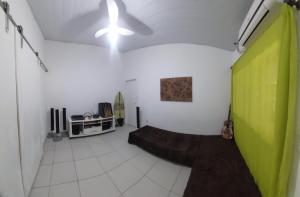 a living room with a green wall and a ceiling at Quarto em Guarapari 5 min da praia in Guarapari