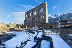 an old building with snow in front of a river at Casa Sofia in Aosta